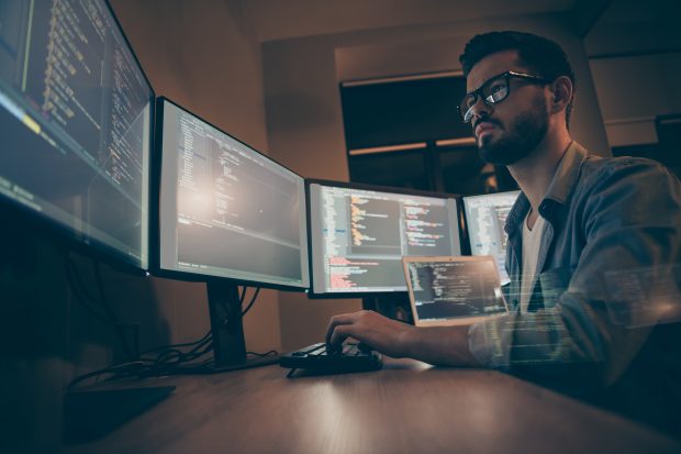 Site Reliability Engineering IT worker looking at multiple computer screens.