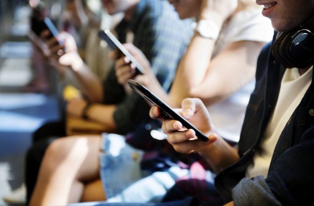 Commuters working on mobile devices while travelling to work.