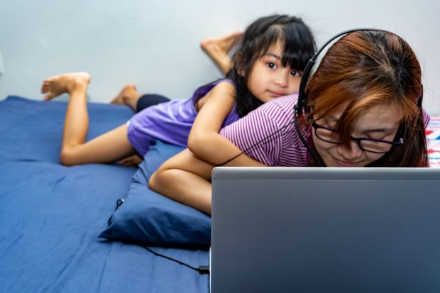 Woman working from home with daughter next to her.