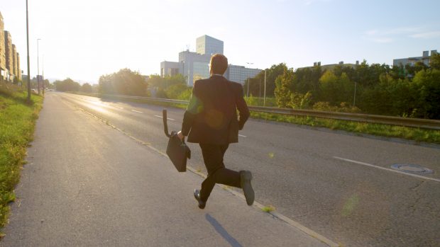 Young man wearing a suit running while holding a briefcase.